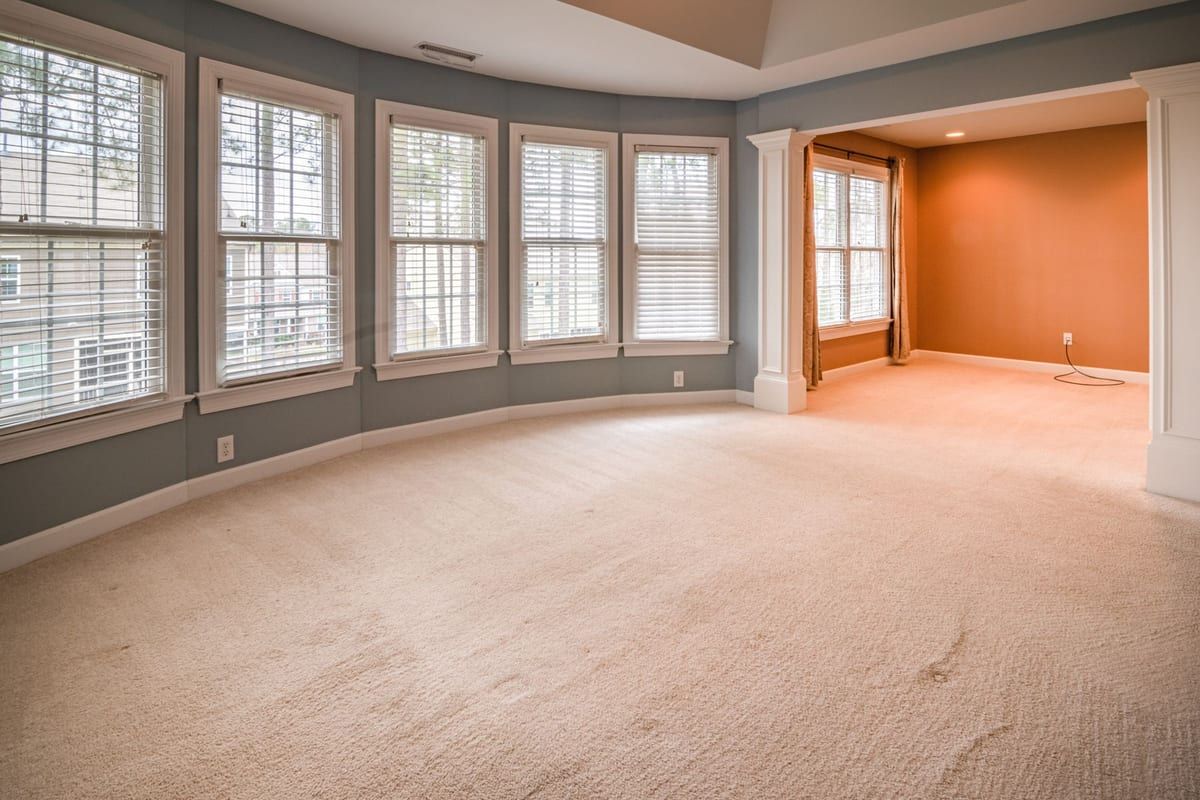 A tired, flattened old carpet in a bay-windowed room